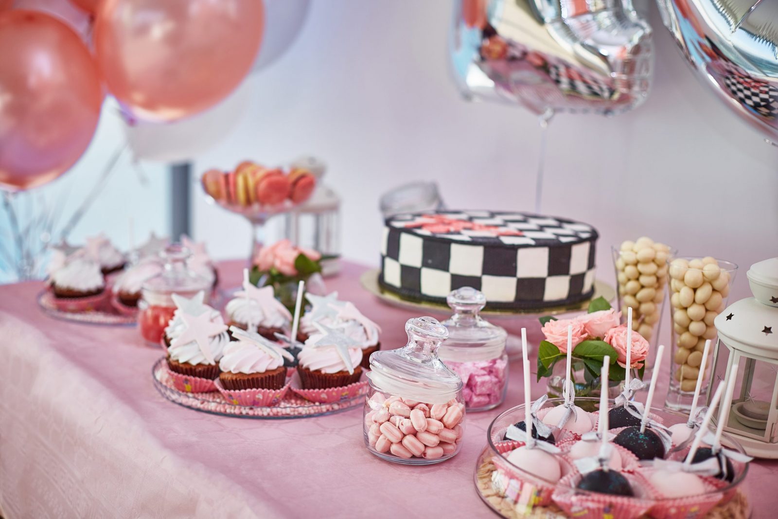 beautiful pink candy bar with cupcakes, pops, cake, marshmallows dragees. balloons around