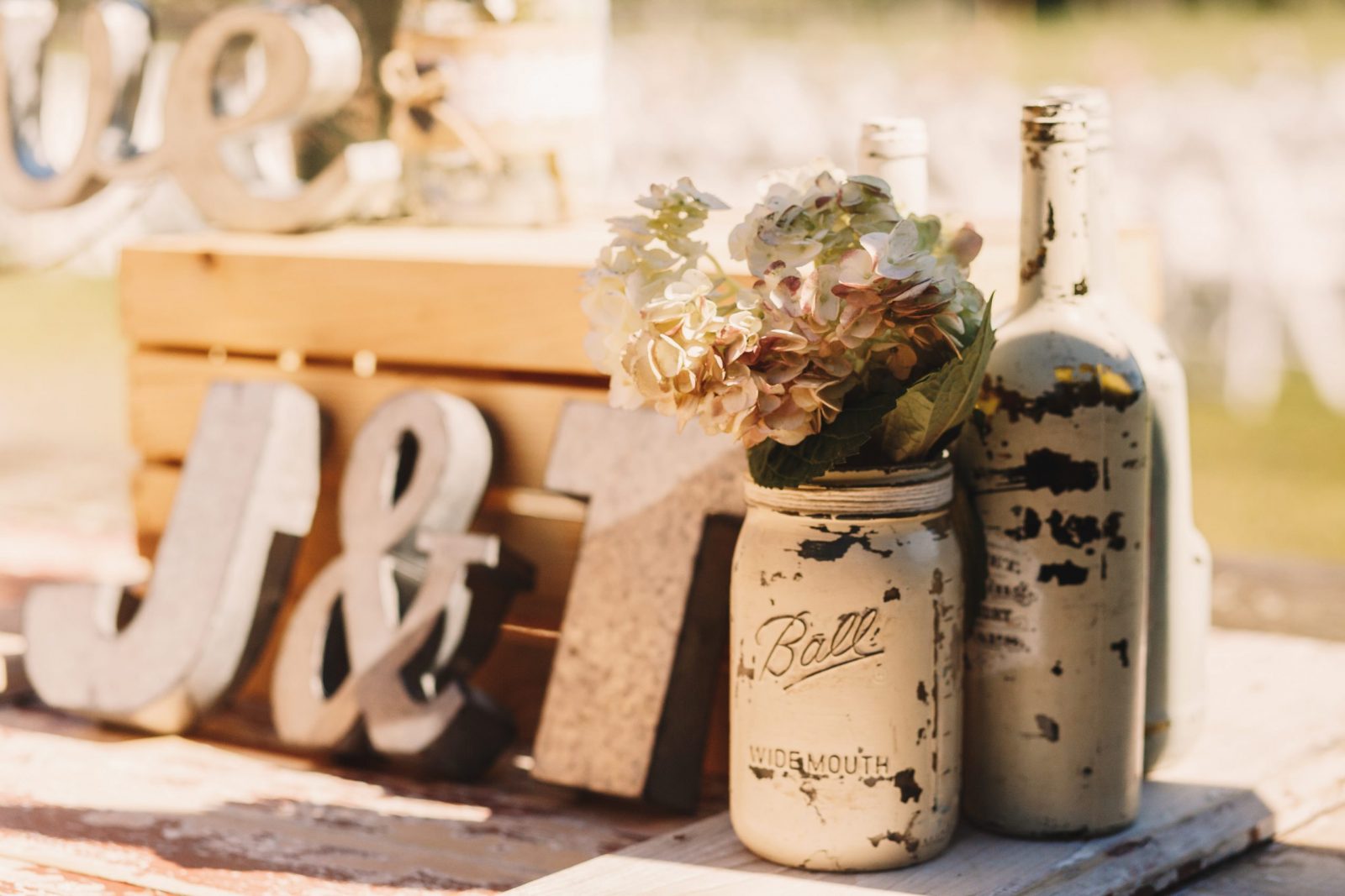 White old bottles with beige flowers stand before wooden newleweds' initials